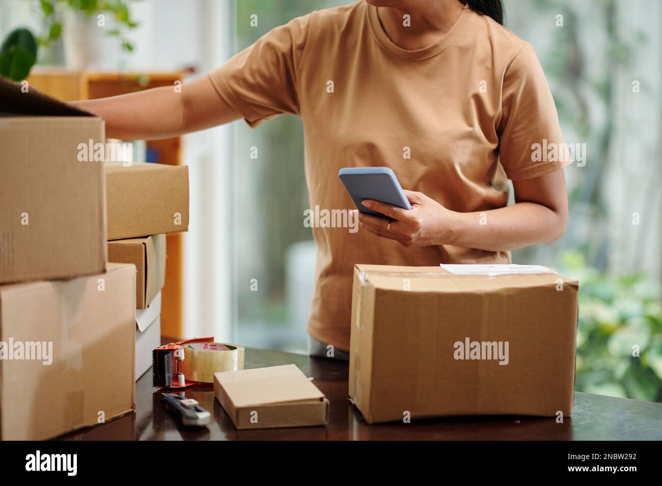 Businesswoman packing orders for customer and scanning stickers on