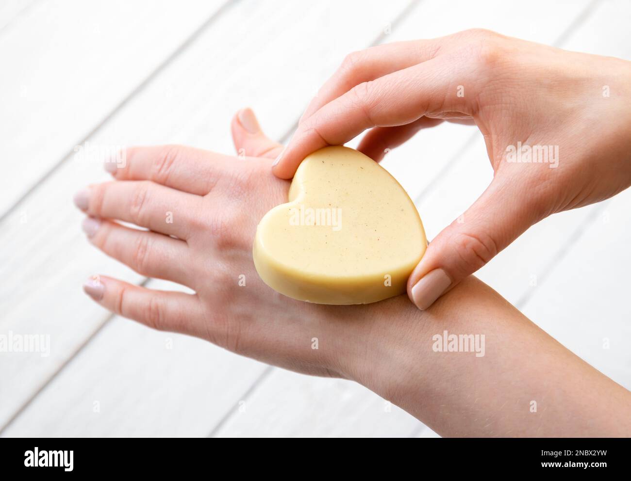Woman hands holding and applying handmade beeswax and shea butter solid moisturizing hand cream. Handmade with all natural ingredients. Stock Photo