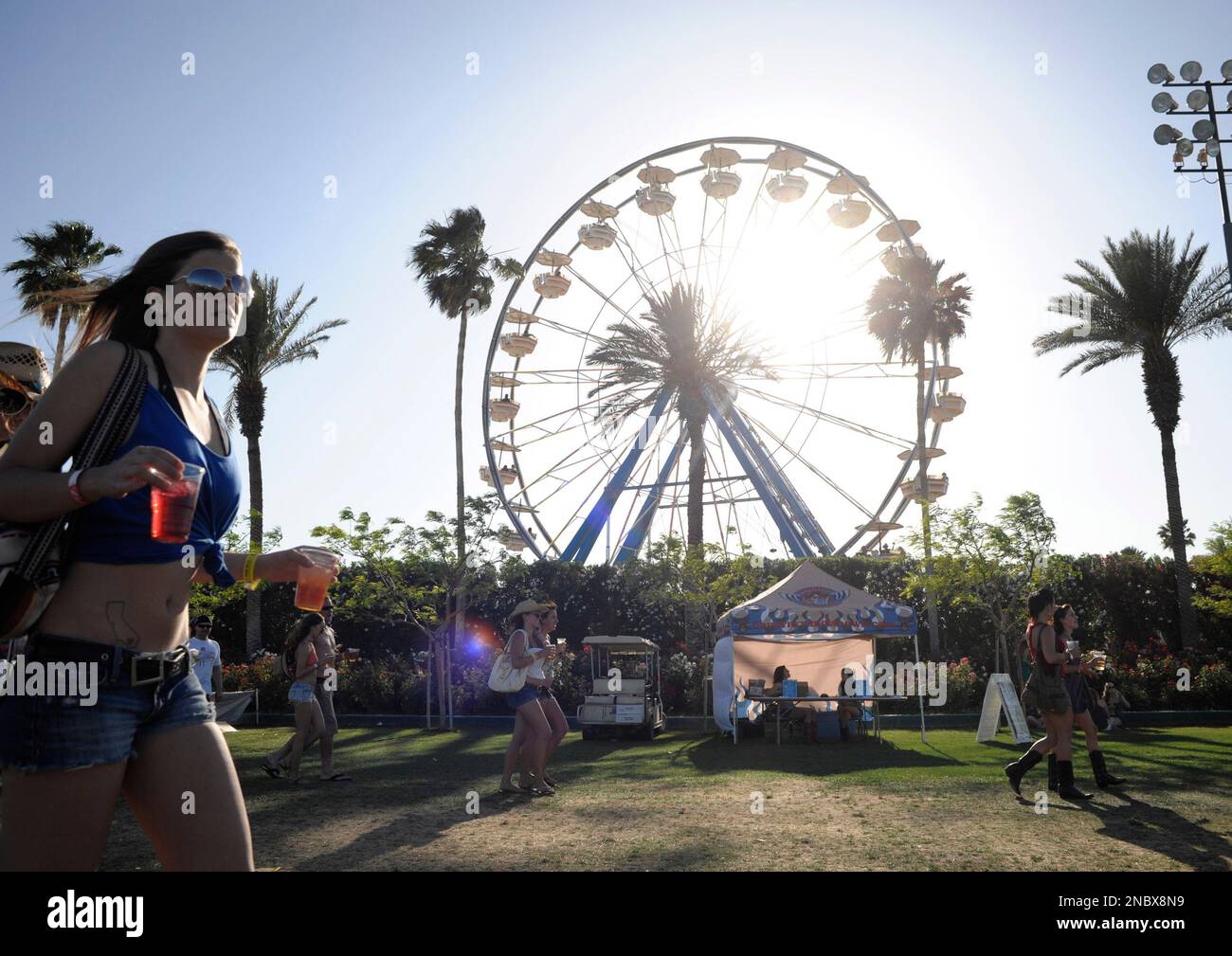 Country music fans walk by a ferris wheel at the Stagecoach Music