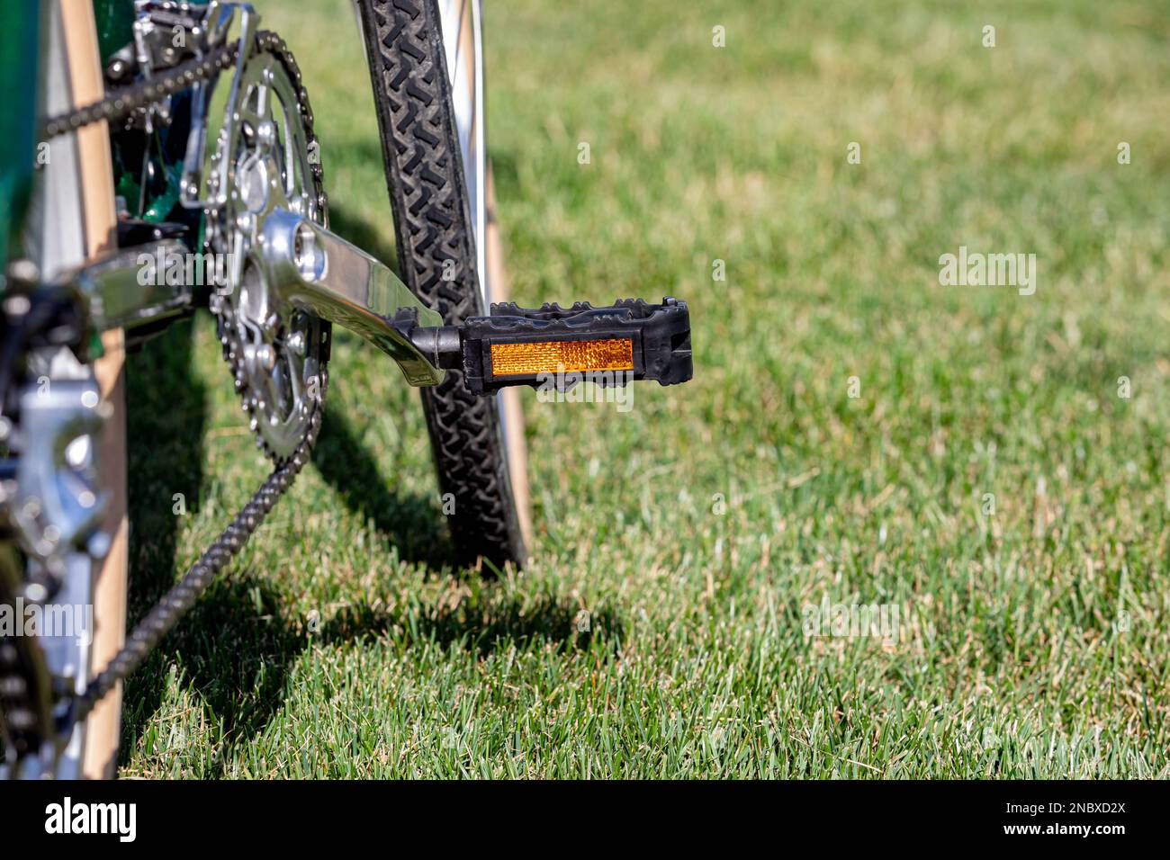 Bicycle with reflector pedal in grass during summer. Cycling, biking, and outdoor exercise concept. Stock Photo