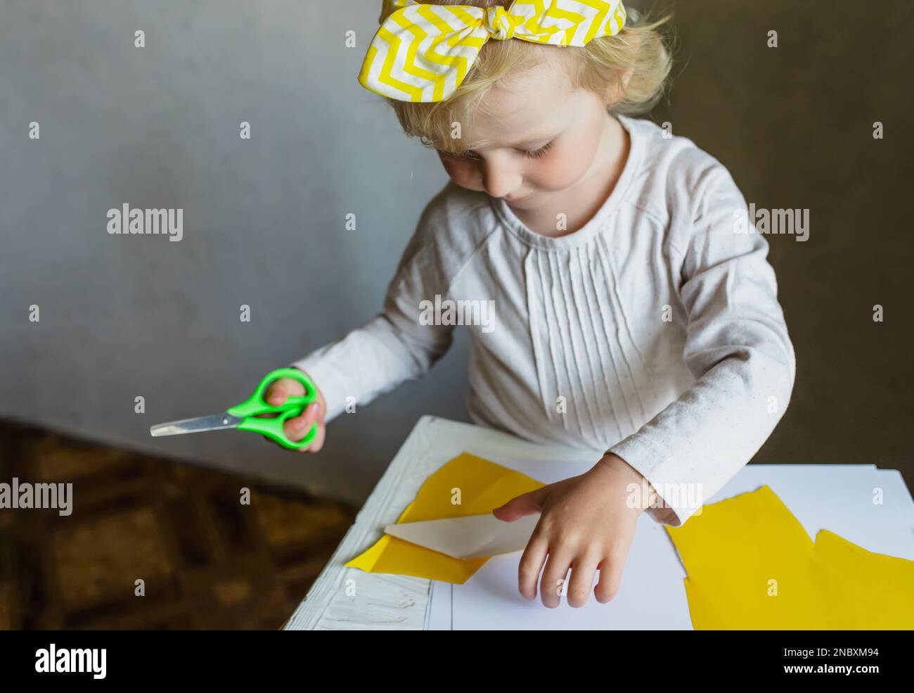Little girl cutting paper. Fine motor skills for children. Teaching scissors skills to