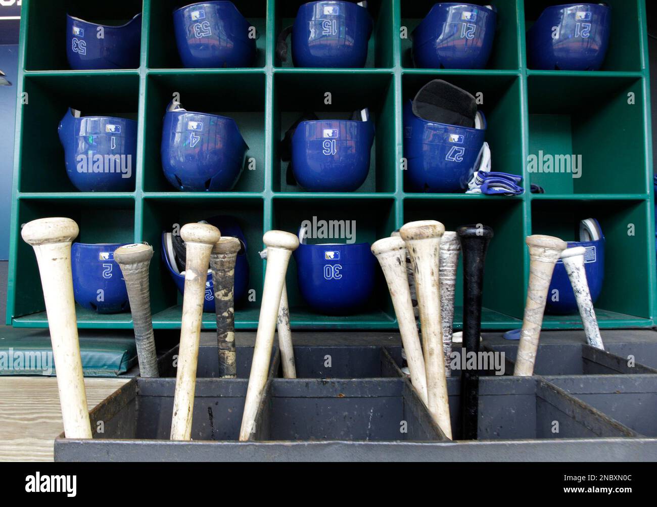 Bats and batting helmets sit in their bins in the visitors dugout before the start of a baseball