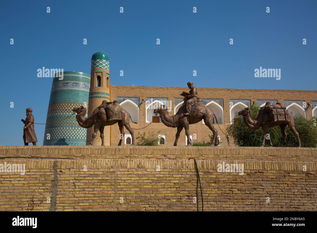 Sculpture of Camel Train, Kalta Minaret (background), Ichon Qala, Khiva, Uzbekistan Stock Photo