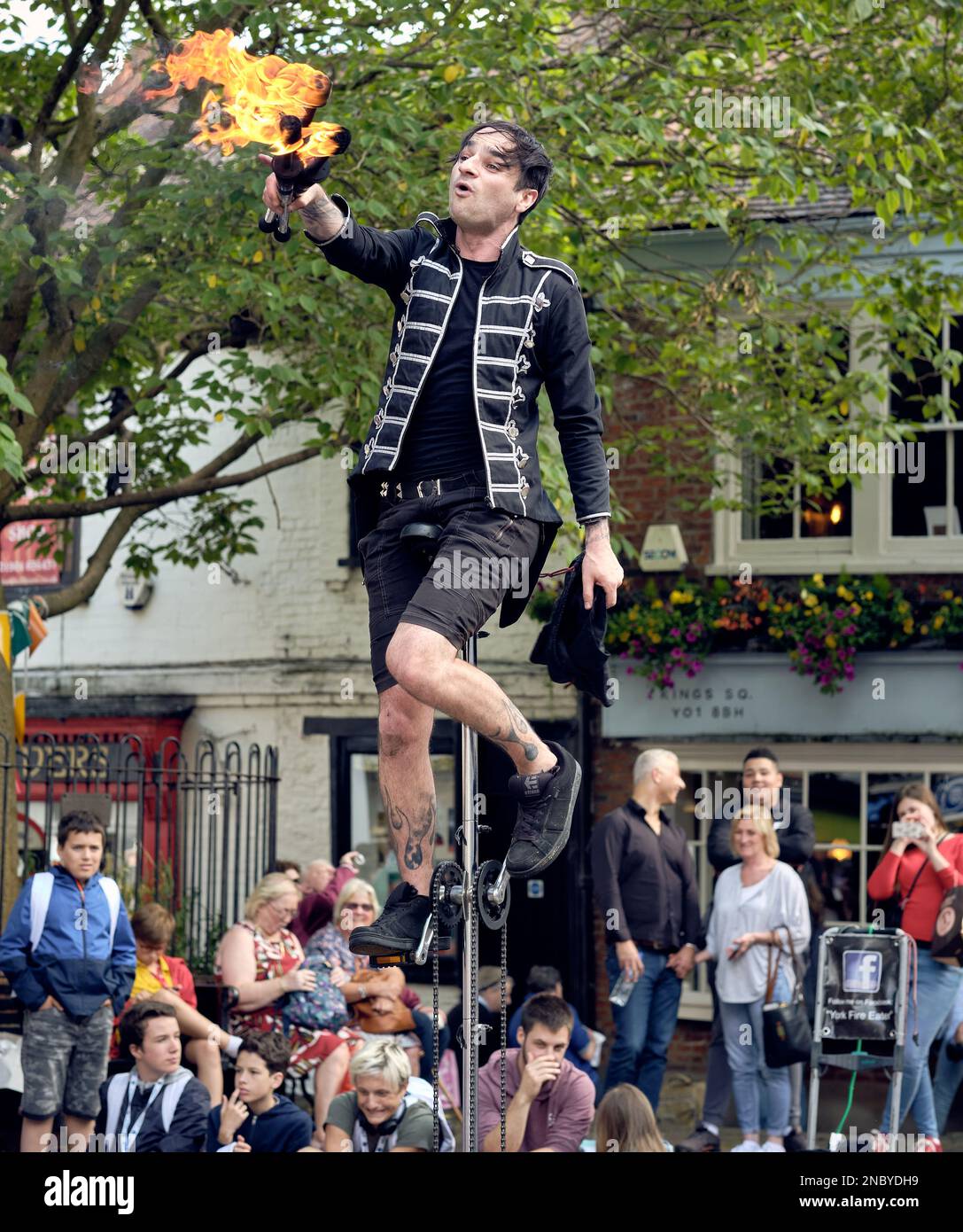 A street entertainer, juggling with clubs on fire, in the centre of York. Bystanders spectate in the background. Stock Photo