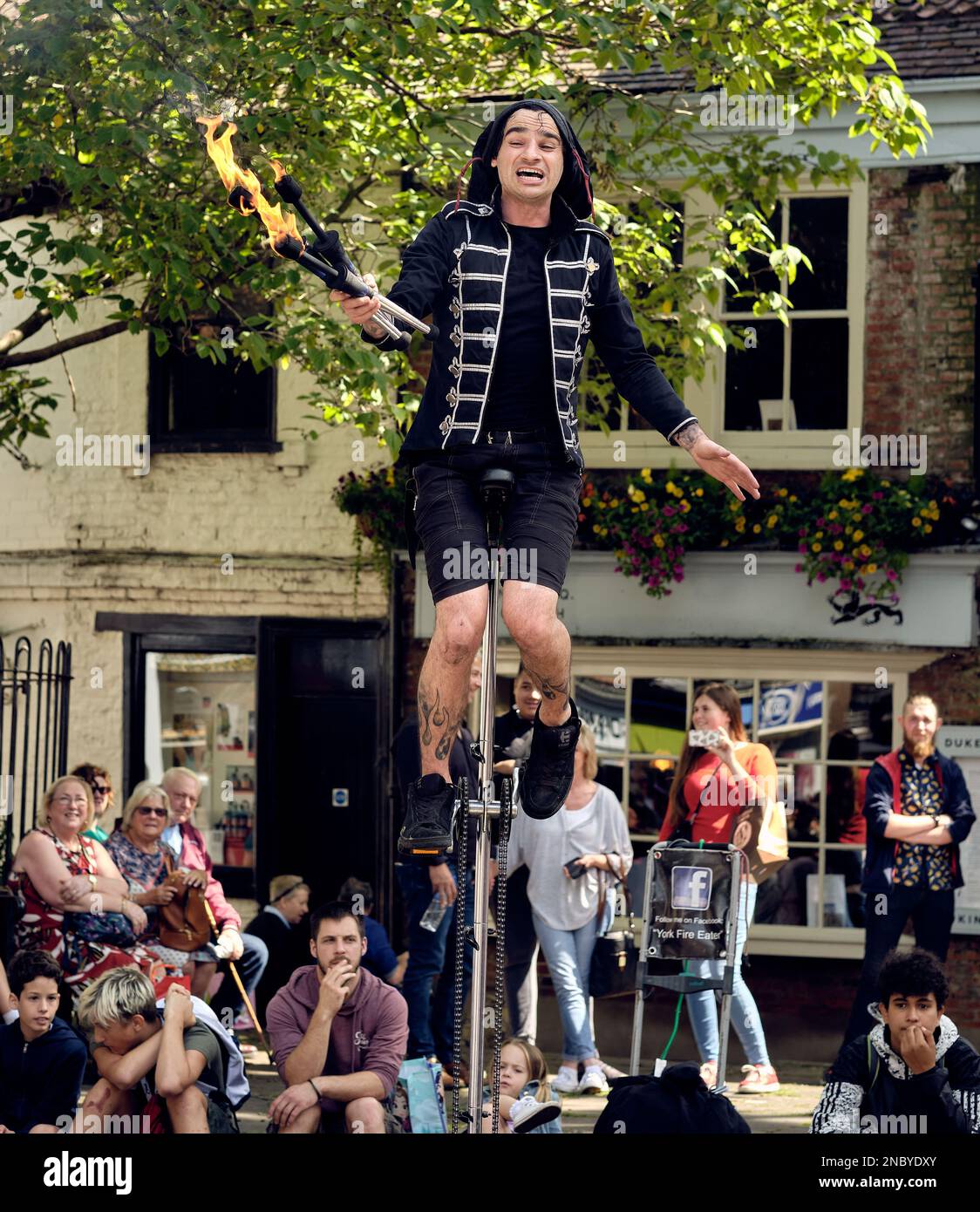 A street entertainer, juggling with clubs on fire, in the centre of York. Bystanders spectate in the background. Stock Photo