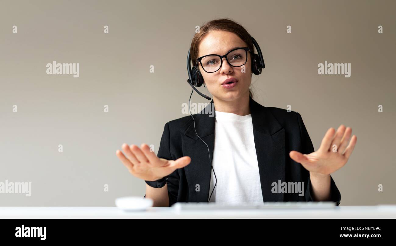 Businesswoman in glasses and headset participating in corporate web conference leading business online meeting. Stock Photo