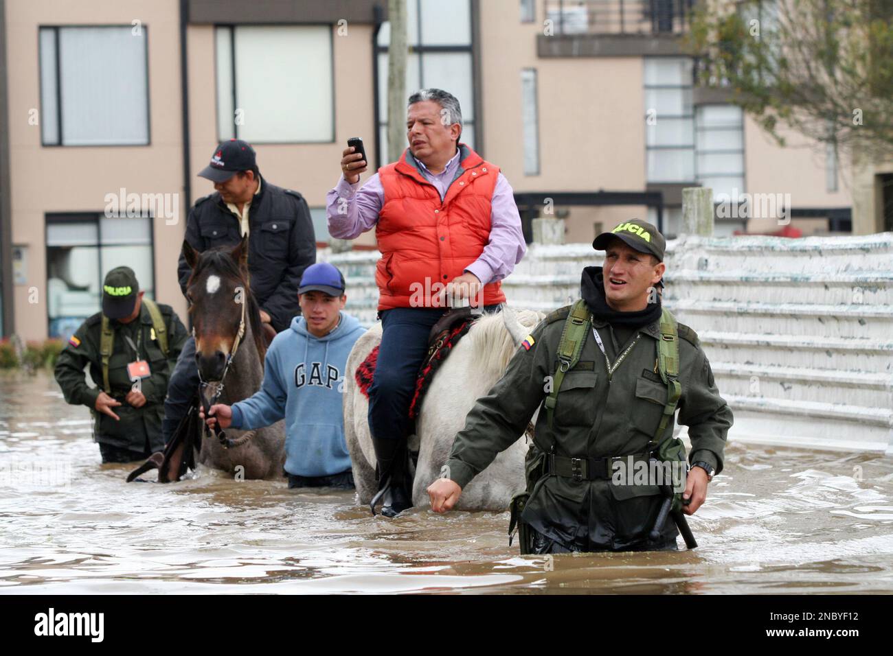 Police officers and residents wade through a flooded street in Chia, on ...