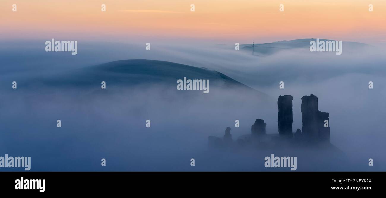 Corfe Castle rising from the misty sunrise viewed from west hill Stock Photo