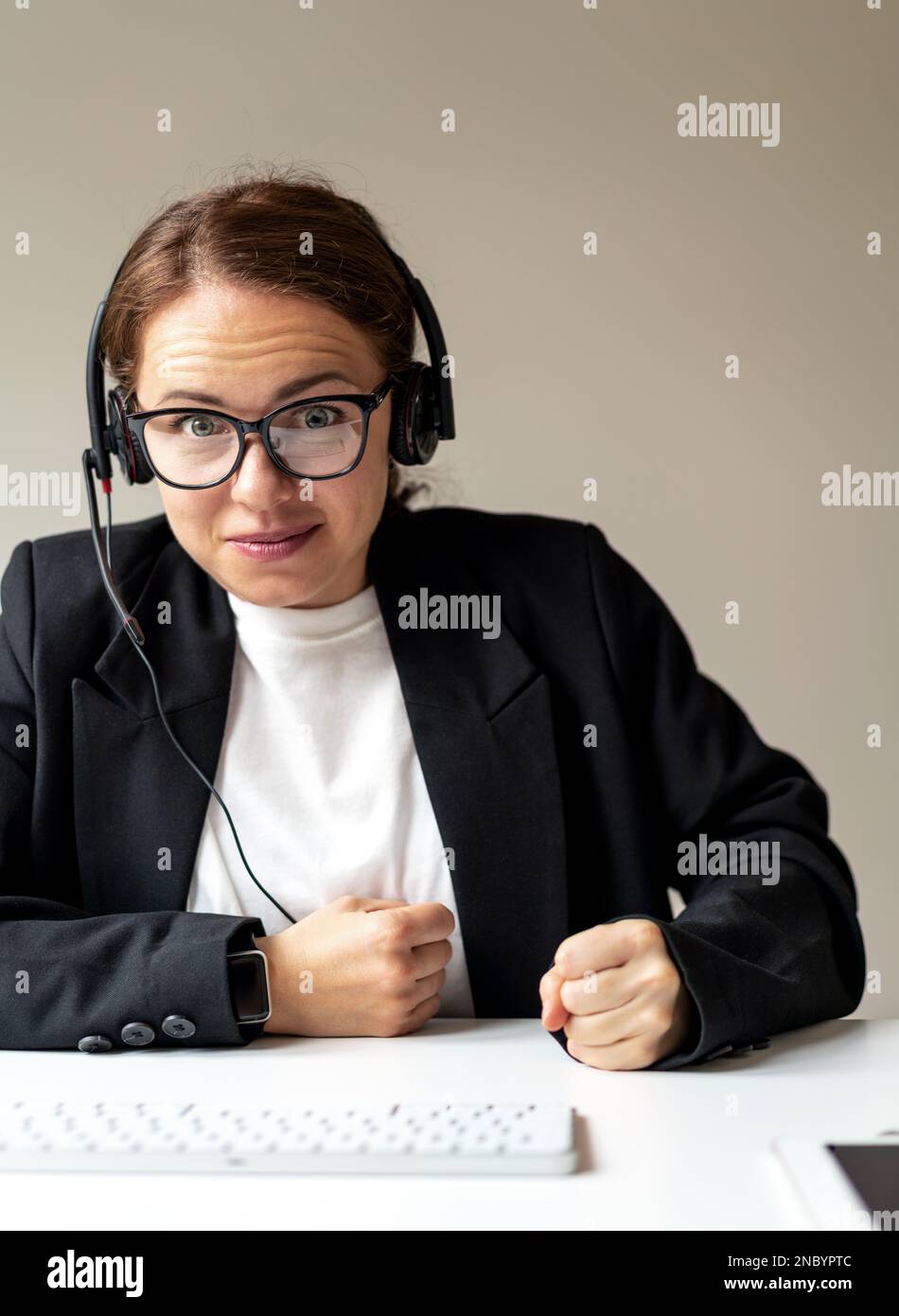 Female manager participating in corporate online meeting with funny facial expressions and slamming fist table. Stock Photo
