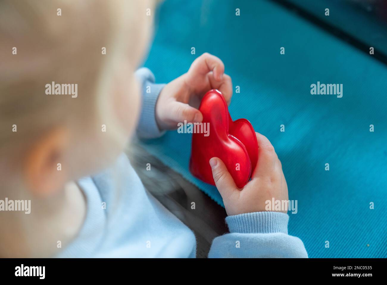 A toddler girl is holding two red hearts Stock Photo