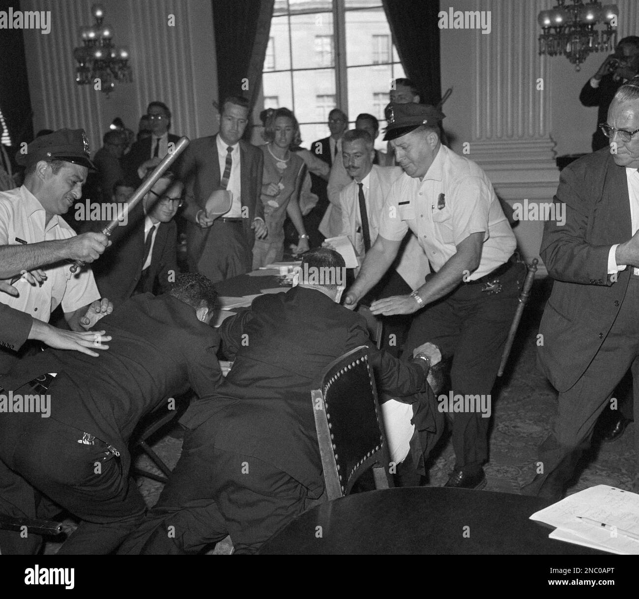 Club-swinging policemen and marshals close in on a man, lying on floor at  lower right, after he leaped onto a table and attacked a witness during a  hearing in Washington on Sept.