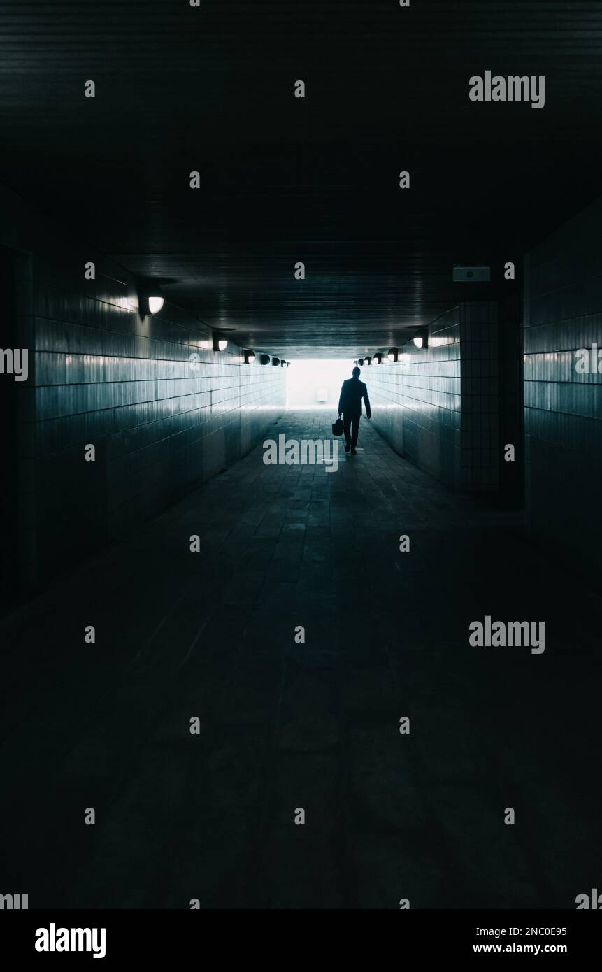 Silhouette of a successful business man walking towards the light at ...