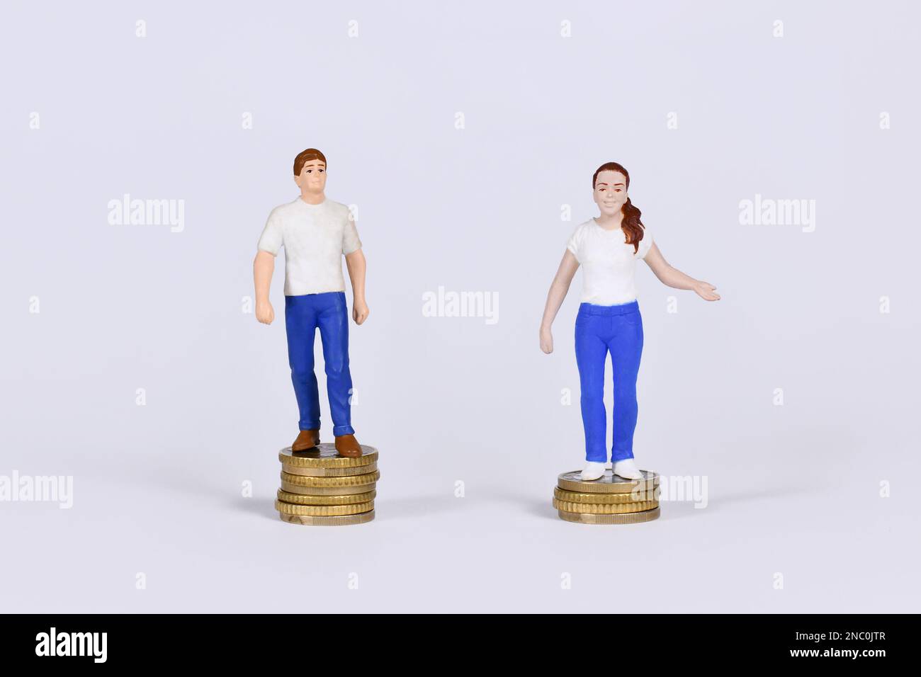 Gender pay gap concept with man and woman standing on different amount of coins Stock Photo