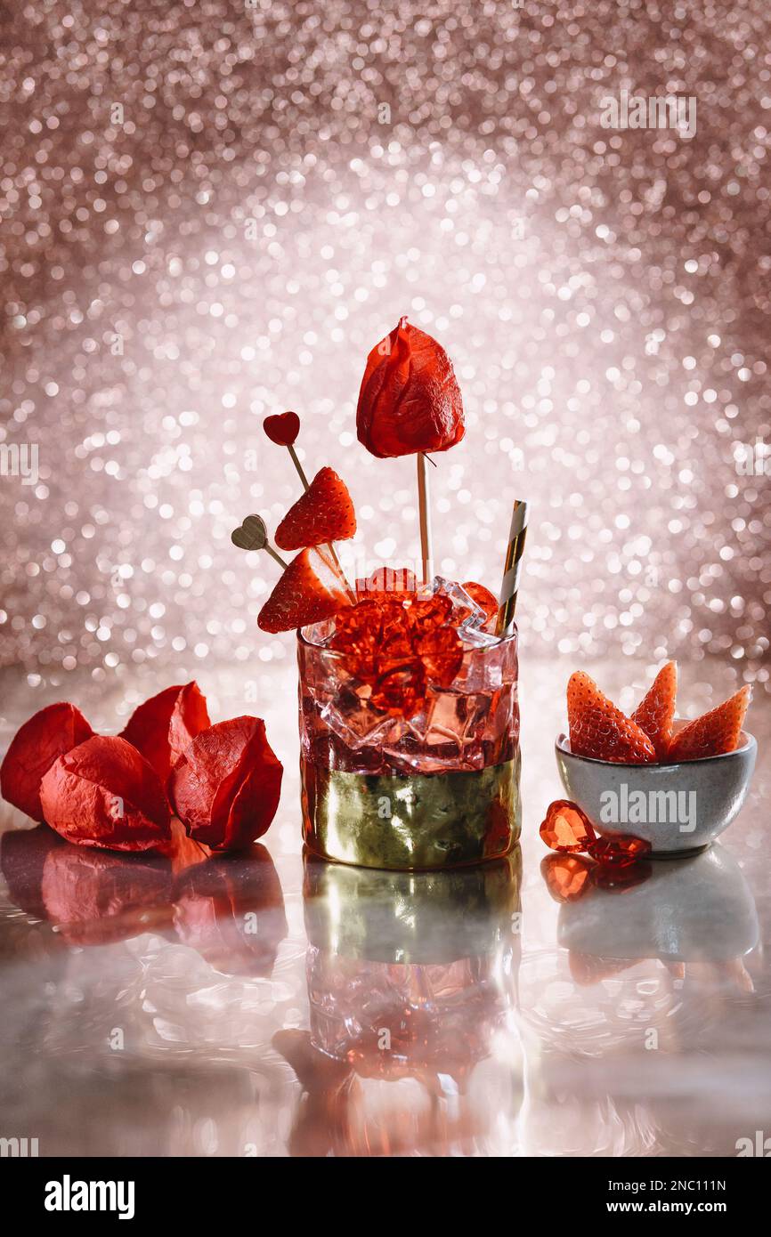 gold and red cocktail for valentine's day, drink with red decoration, strawberries and red hearts Stock Photo