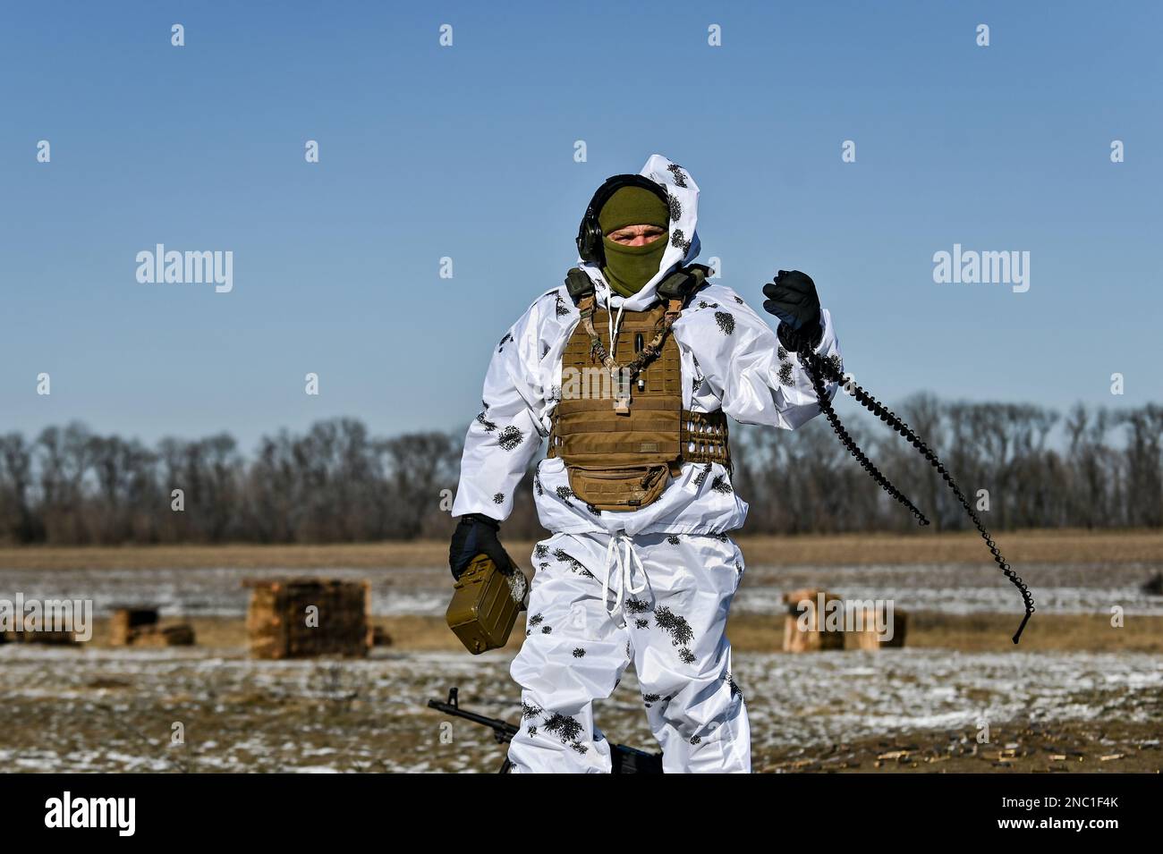 ZAPORIZHZHIA REGION, UKRAINE - FEBRUARY 8, 2023 - A soldier in a winter camouflage suit holds an ammunition box and cartridge belt as the training ses Stock Photo