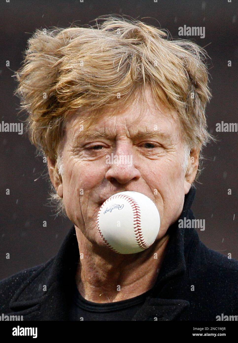Actor Robert Redford flips a ball in the air before throwing out a