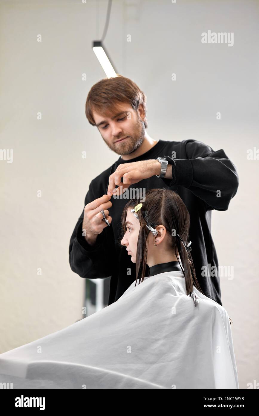 Professional male hairdresser cutting female hair in salon Stock Photo