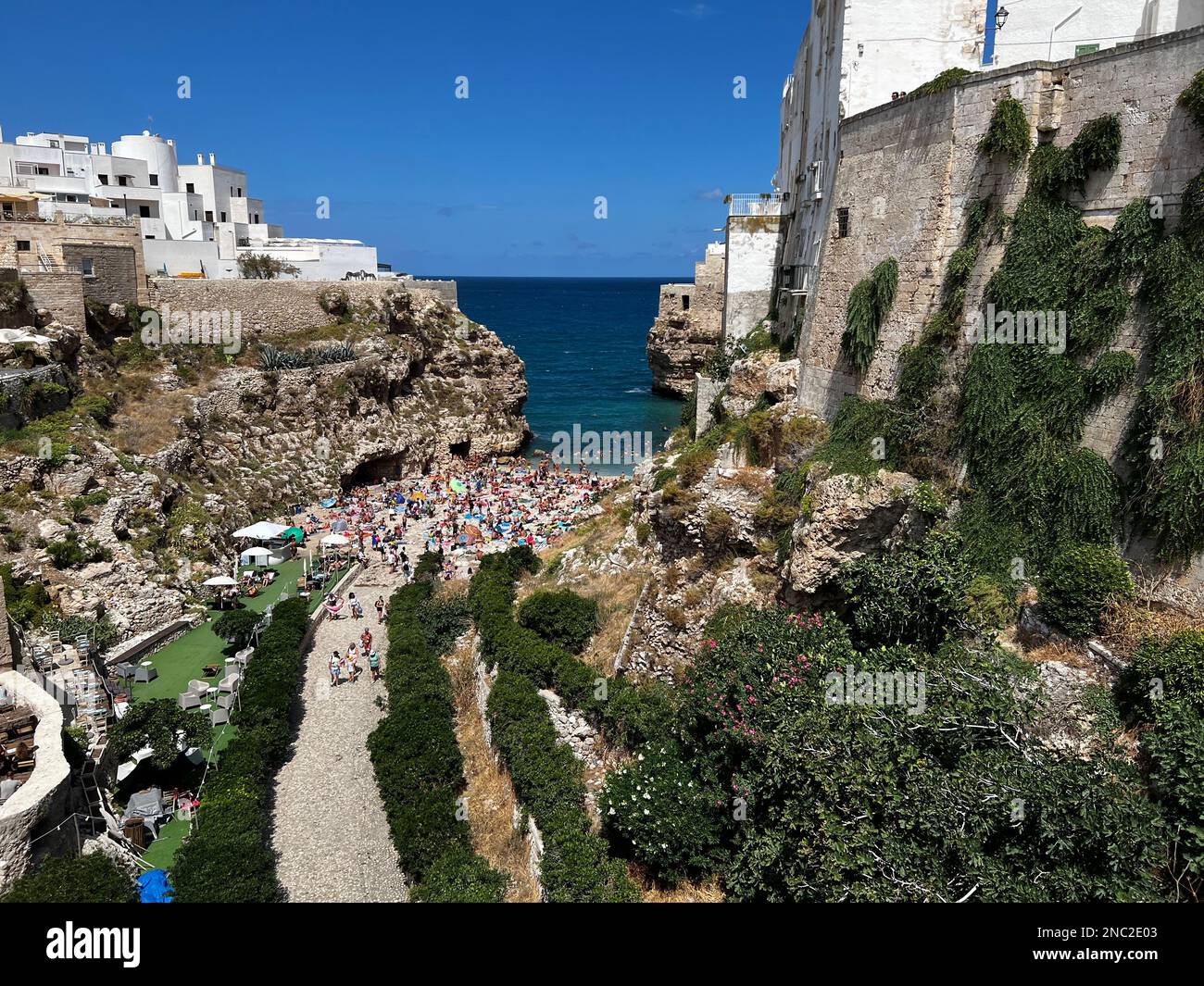 Sunbathers enjoy the Lido Cala Paura Beach in Polignano a Mare, Italy.  Surrounded by dramatic cliffs and crystal clear waters of the Adriatic Sea, it Stock Photo