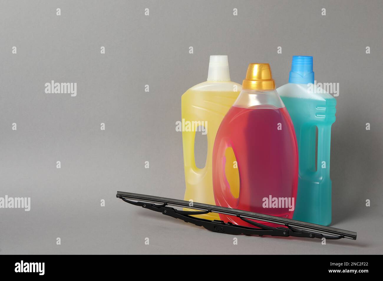 Bottles of windshield washer fluids and wiper on grey background. Space