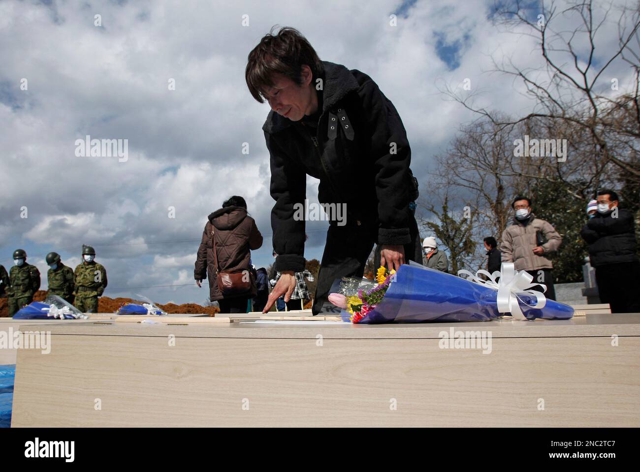 A Japanese mourner touches the coffin for a loved one during a mass