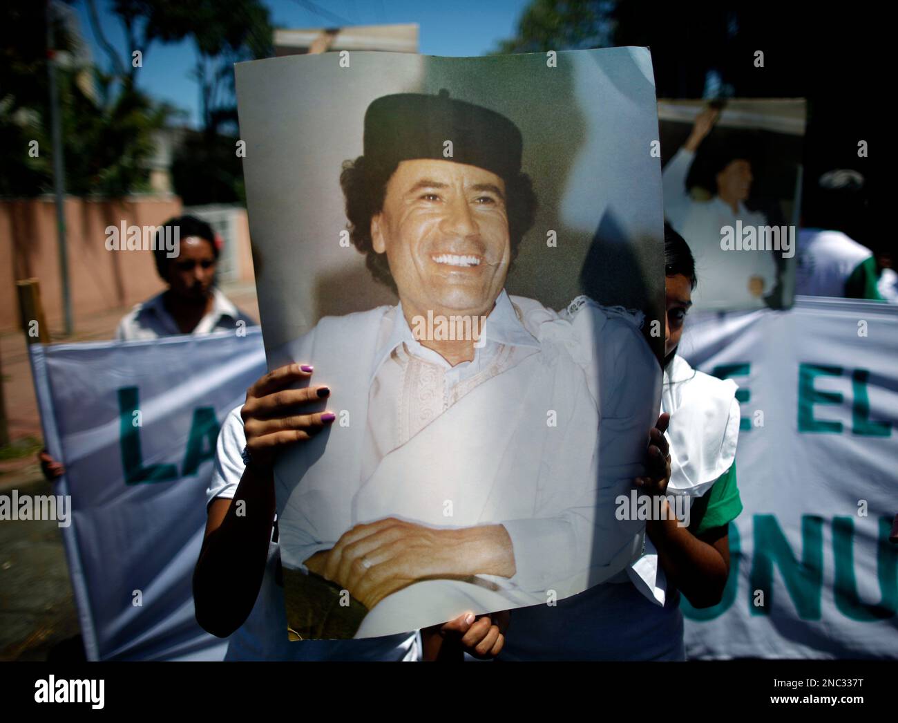 Supporters of Nicaragua's President Daniel Ortega hold portraits of Libyan leader Moammar Gadhafi at a demonstration in favor of Gadhafi outside the Libyan embassy in Managua, Nicaragua, Thursday March 24, 2011. (AP Photo/Esteban Felix) Stock Photo