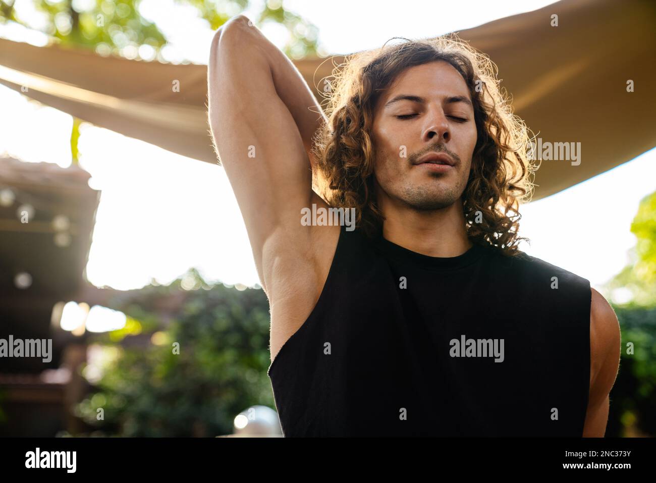 Young curly white man doing workout and stretching his body outdoors Stock Photo