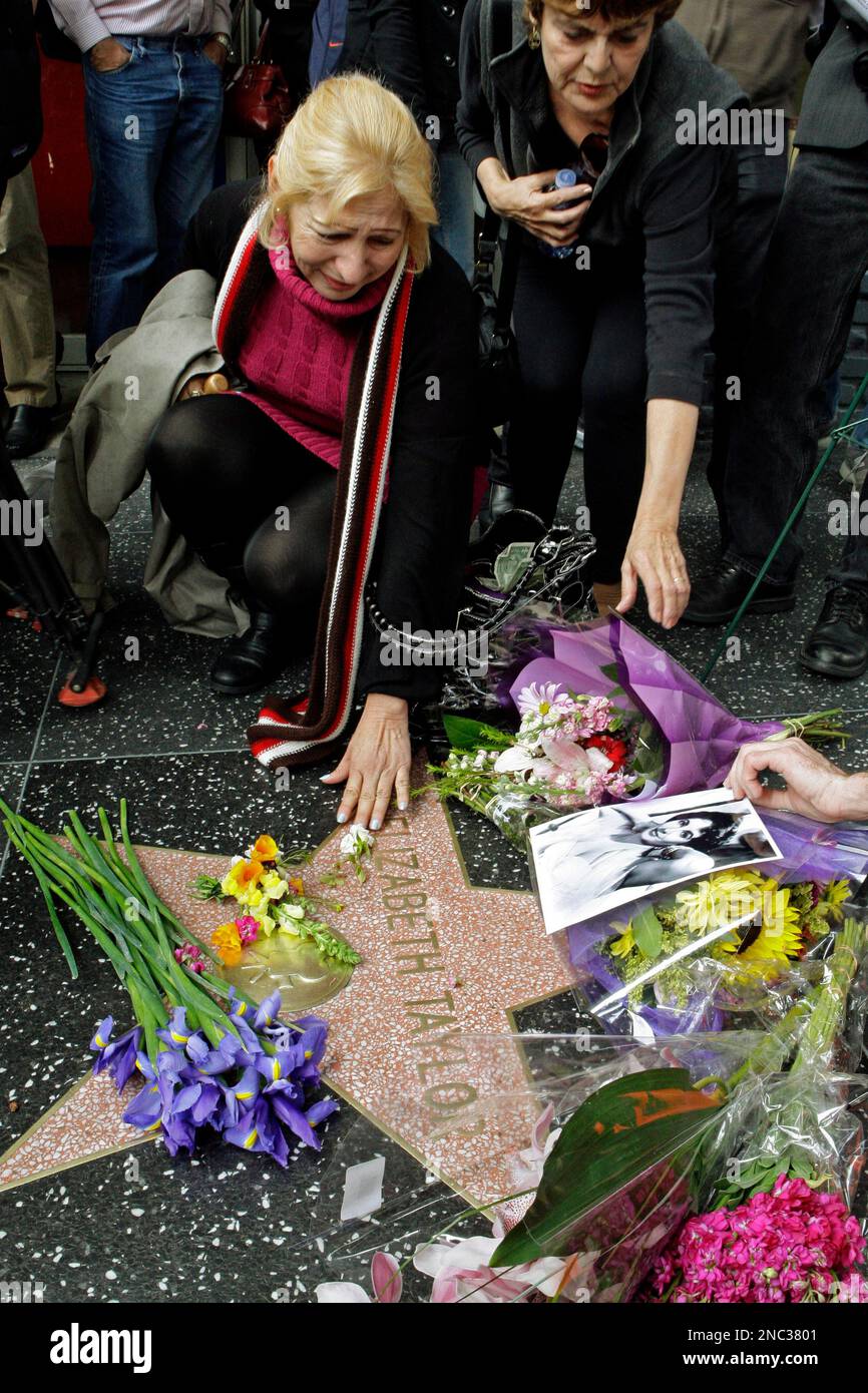 A woman reaches down to touch Elizabeth Taylor's star on the Hollywood