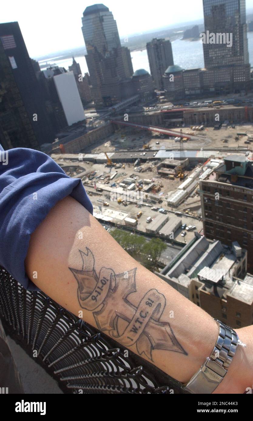 Charlie Ross shows off his Sept. 11 tattoo depicting a cross, the date, and the tower and floor from which he escaped, Aug. 15, 2002, outside of the World Trade Center site