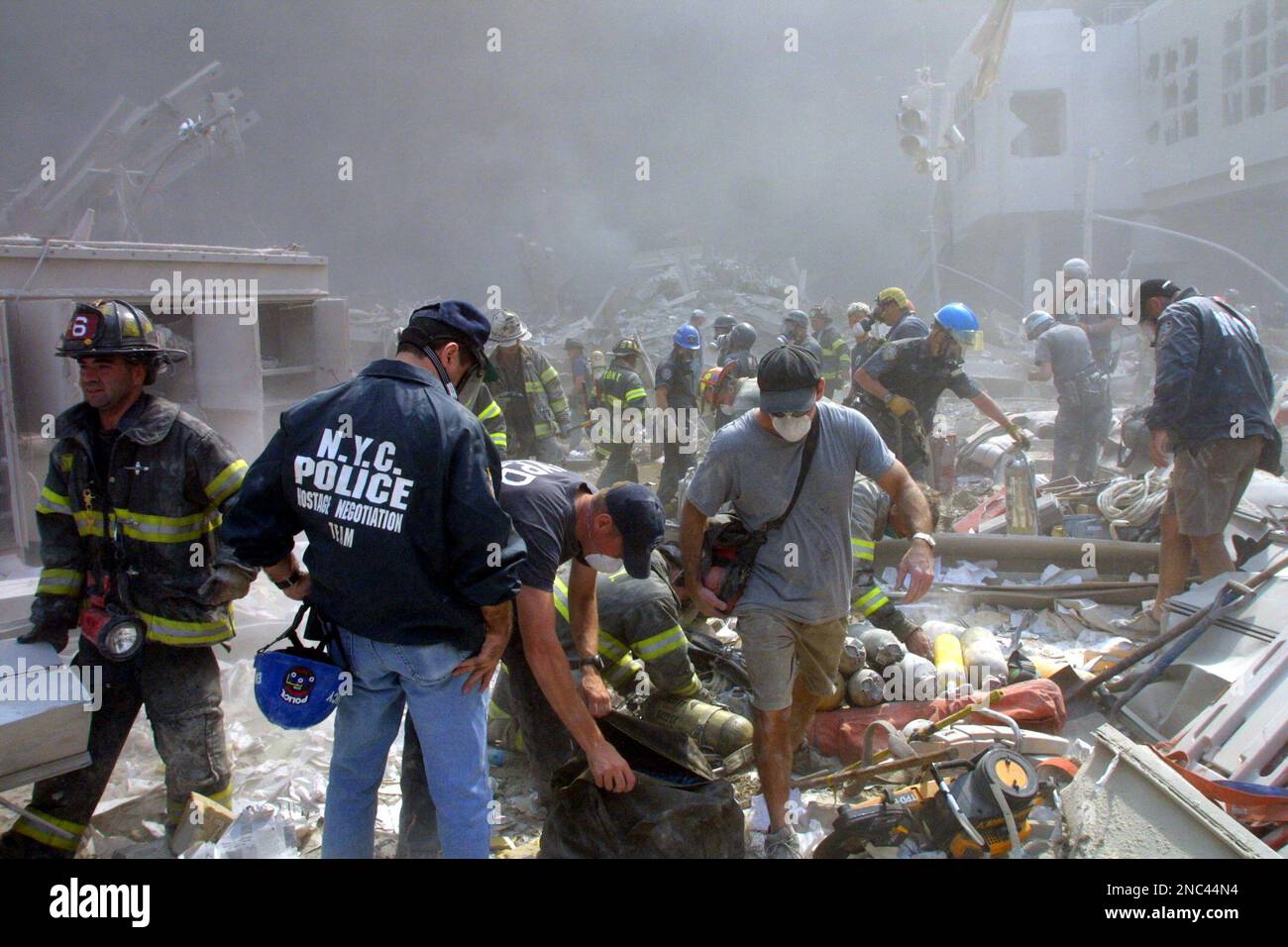 Rescue workers gather supplies as they search through the rubble in the ...