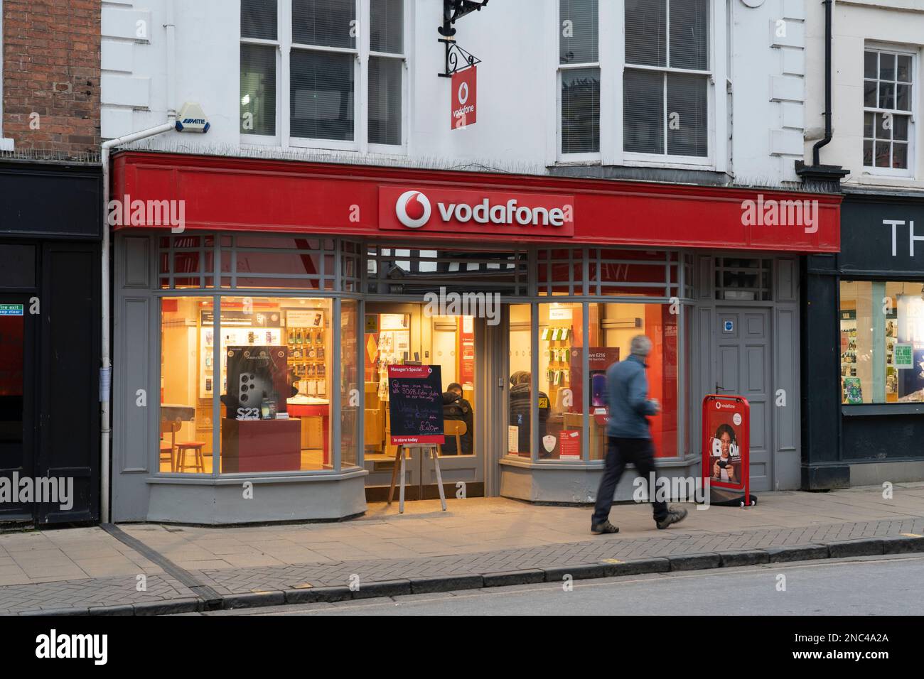 A man walks past the exterior of a Vodafone store on the High Street in Stratford upon Avon, England. Concept: telecoms industry, telecommunications Stock Photo