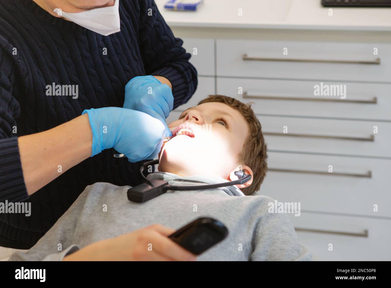 Kid in headphones watches TV at a dentist's appointment. A boy in