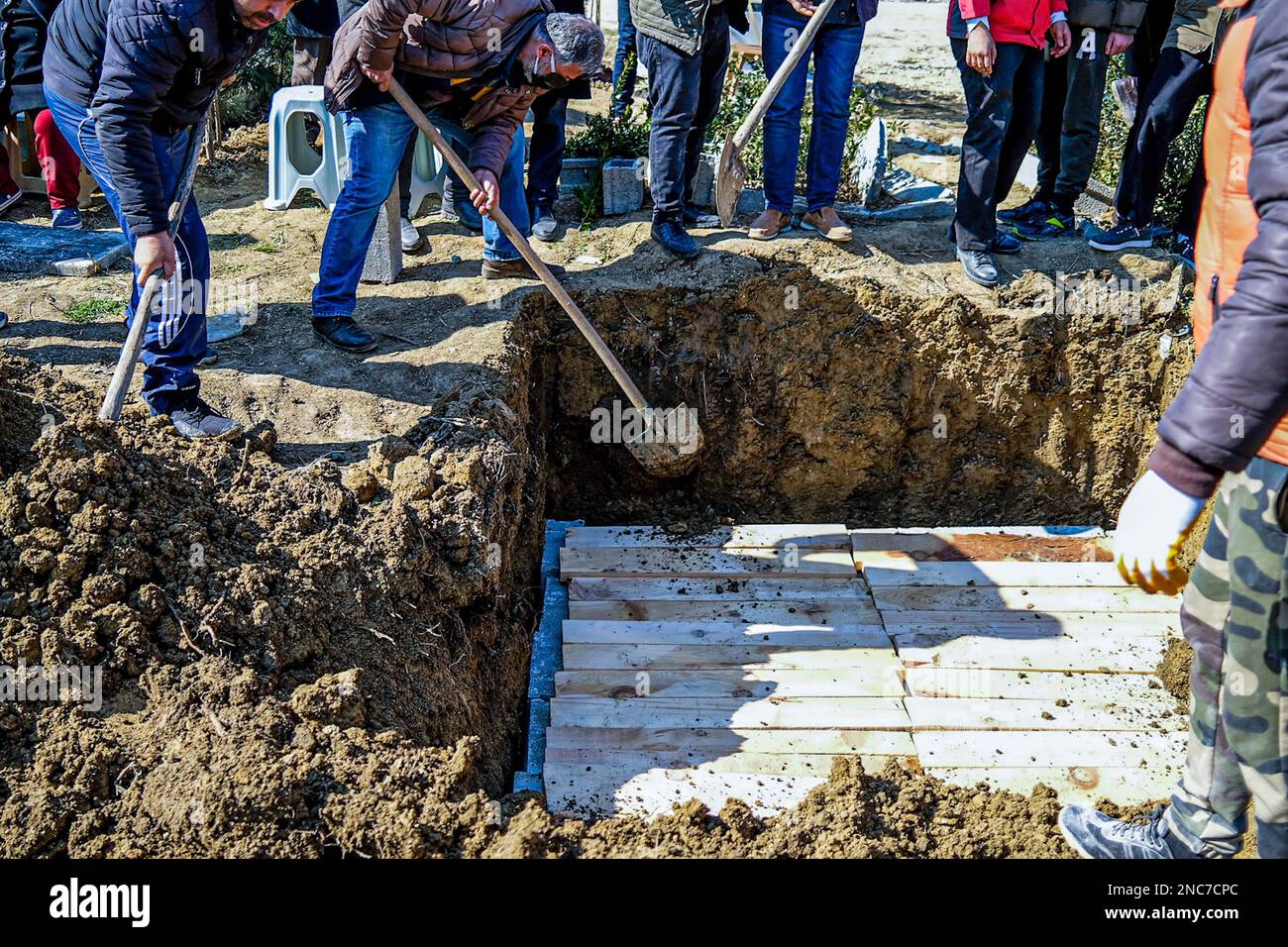 People throw soil on the grave during the burial. A family buried their