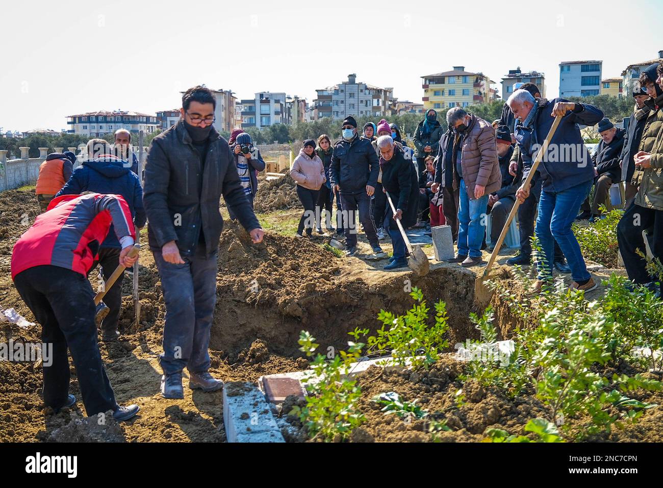 Mourners throw soil on the grave during the burial of the three