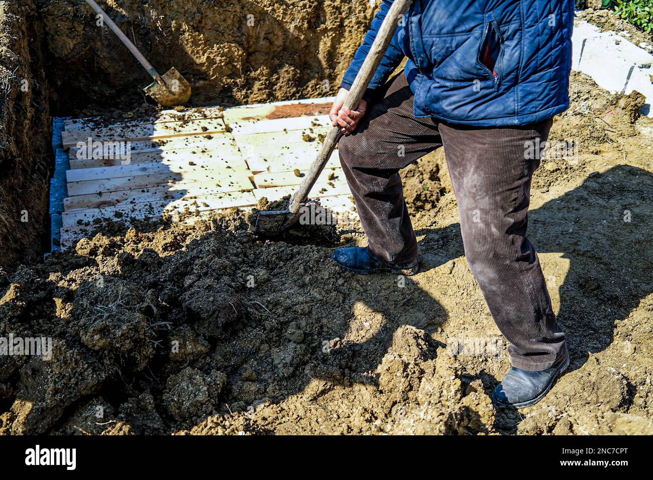 Mourners throw soil on the grave during the burial of the three