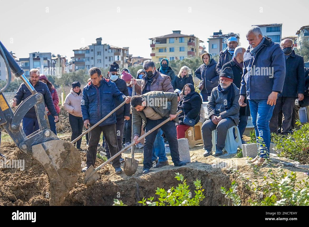 Mourners throw soil on the grave during the burial of the three