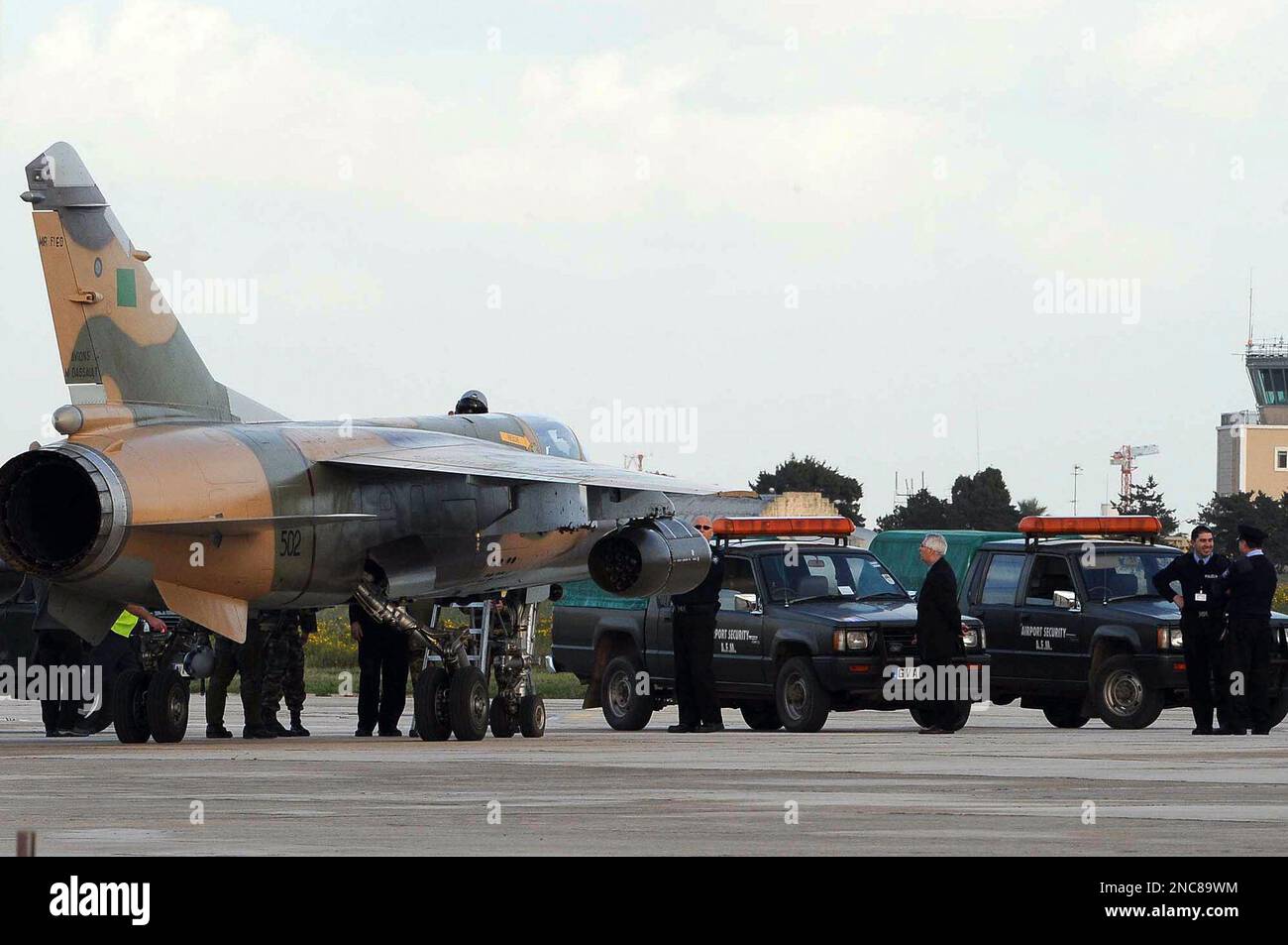One of two Libyan Air Force Mirage jet fighters to land in Malta, is surrounded by Maltese police after it landed in Malta's International airport, Monday, Feb. 21, 2011. (AP Photo/Lino Azzopardi) Stock Photo