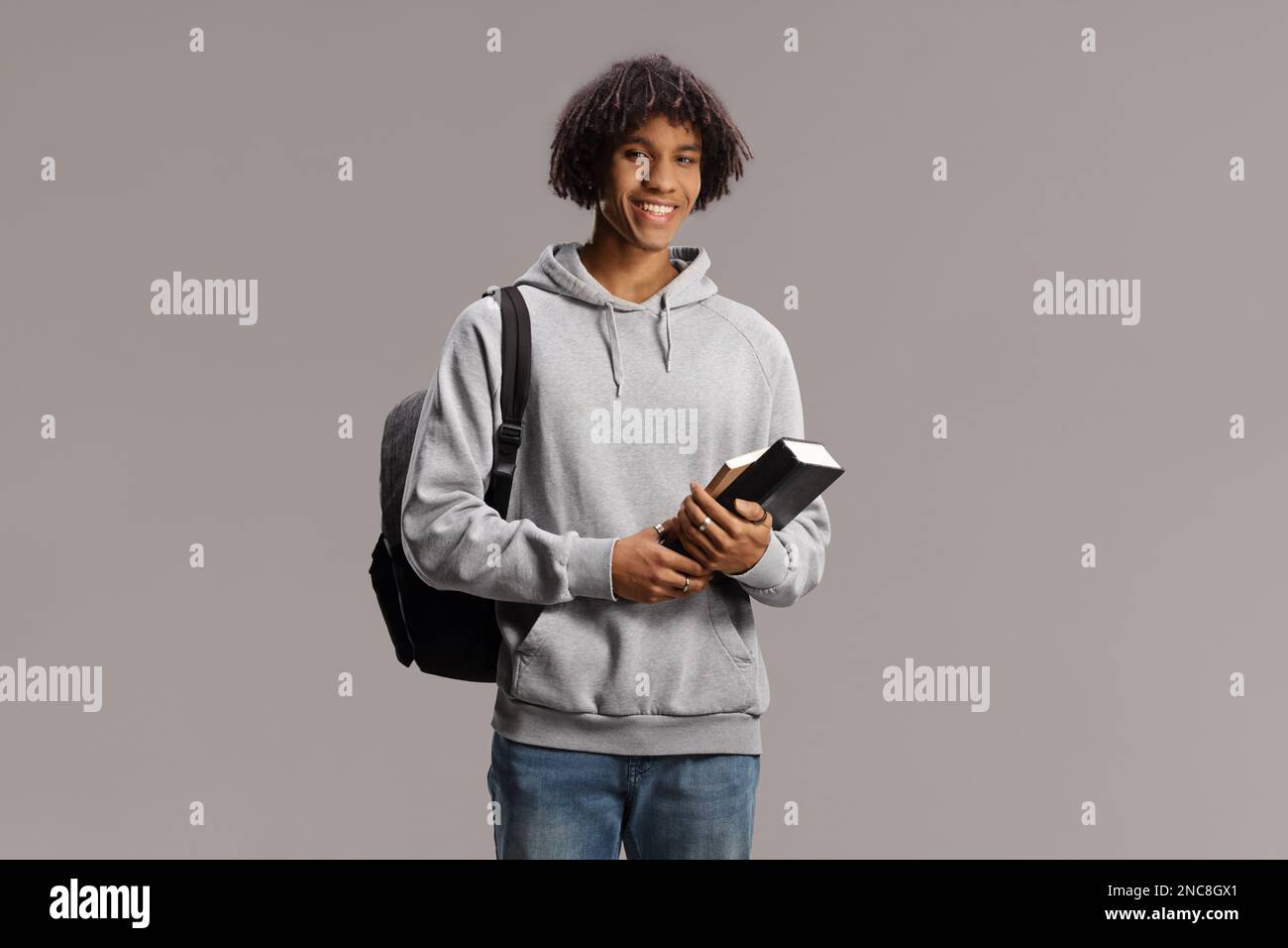 African american male student with a backpack holding books and smiling ...