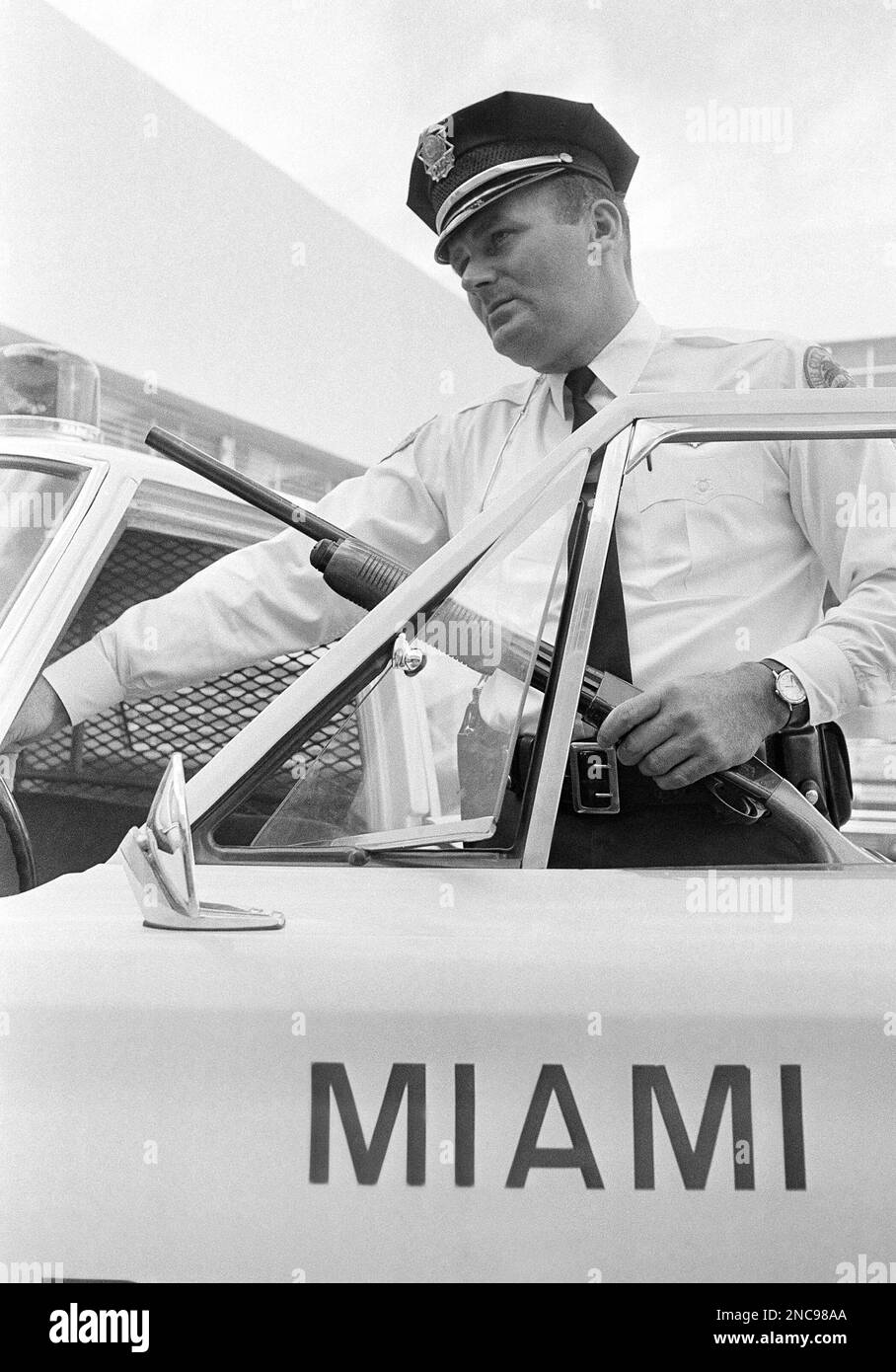 Carrying a 12 gauge shotgun Miami Patrolman Norman Evans gets into
