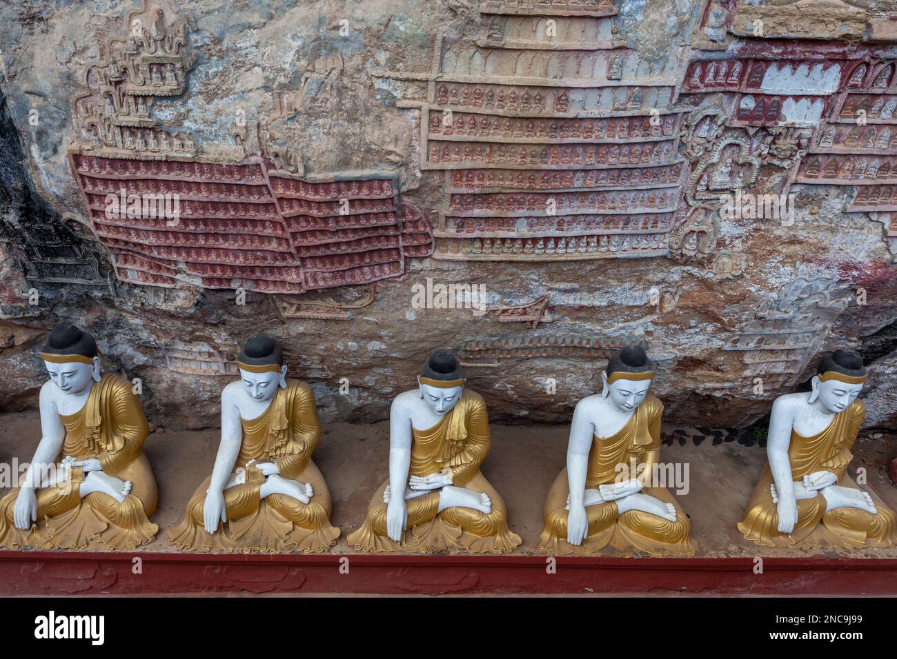 Row of Buddha statues in Kaw Goon cave with carvings in Myanmar. Stock Photo