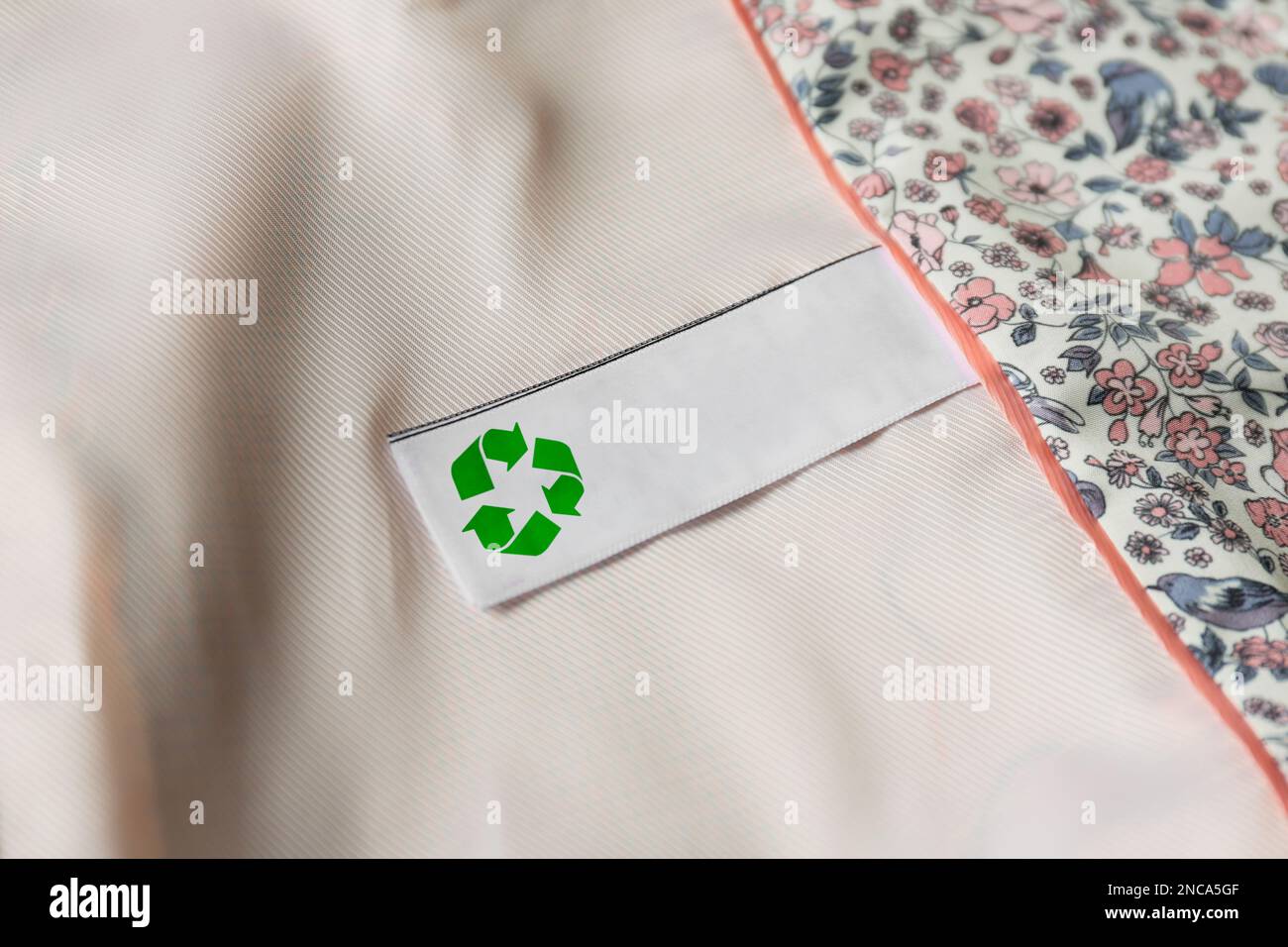 Clothing label with recycling symbol on light garment, closeup Stock