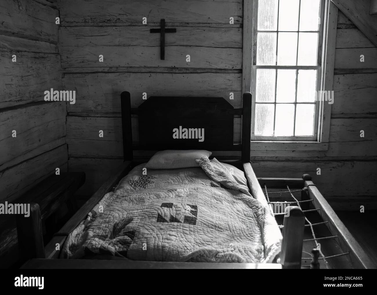 A wooden antique rope bed from 1800s with a cross on the wall from a historic farmhouse in