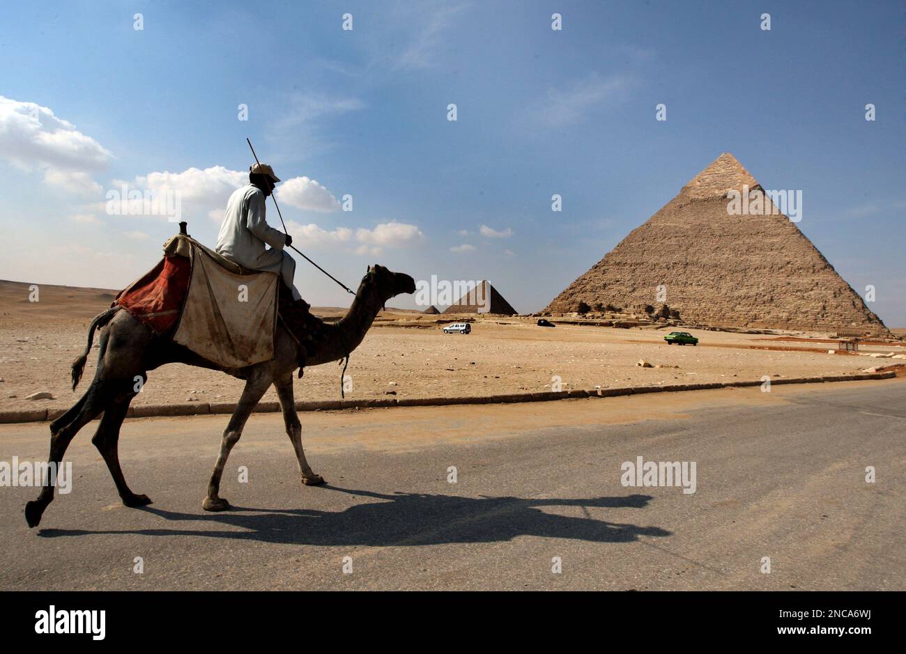 An Egyptian camel rider waits for tourists as he passes by the Pyramids ...