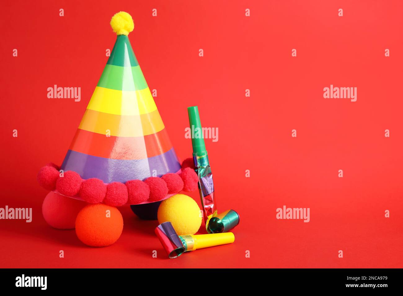 Party cap, blowers and clown noses on red background, space for text Stock Photo