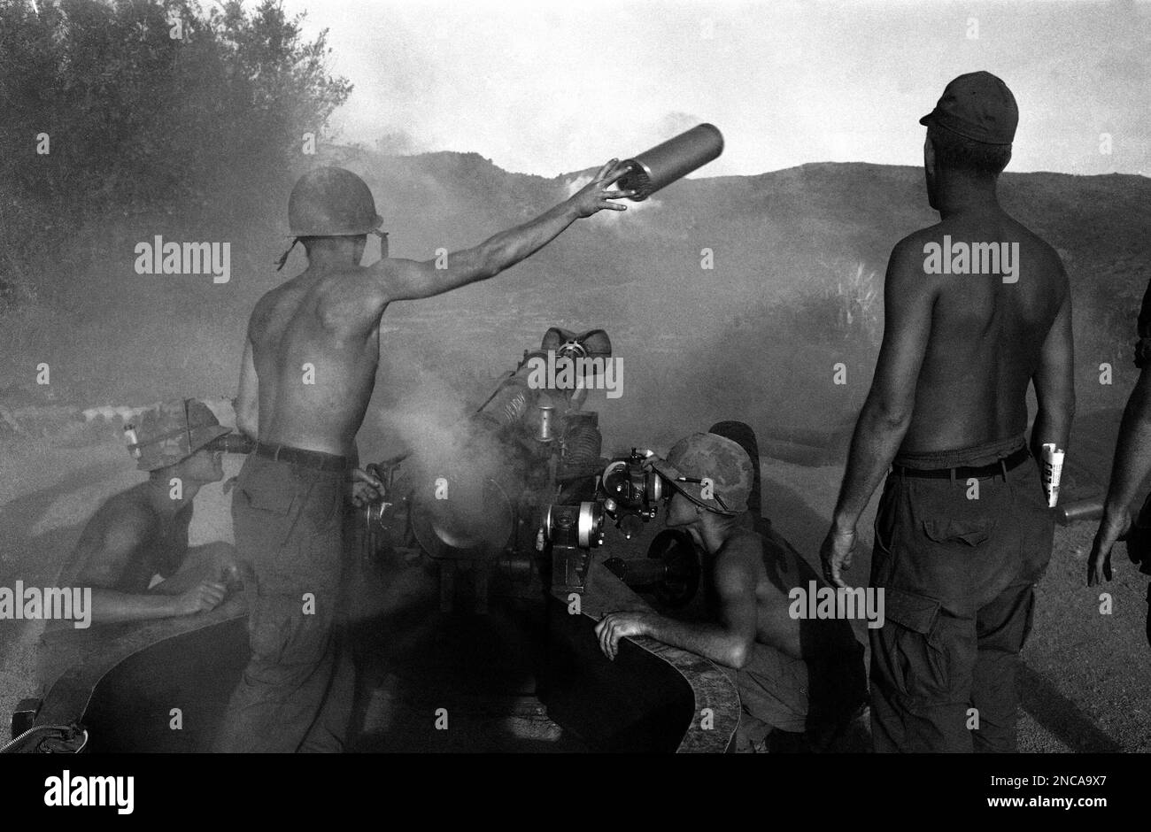 Artilleryman discards a spent shell casing as smoke rises from breech ...