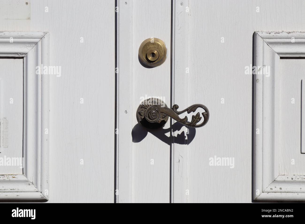 bronze floral metal door handle on white wooden door, old wooden door with metal handle. Old white garden doors. locked door, closed doors Stock Photo