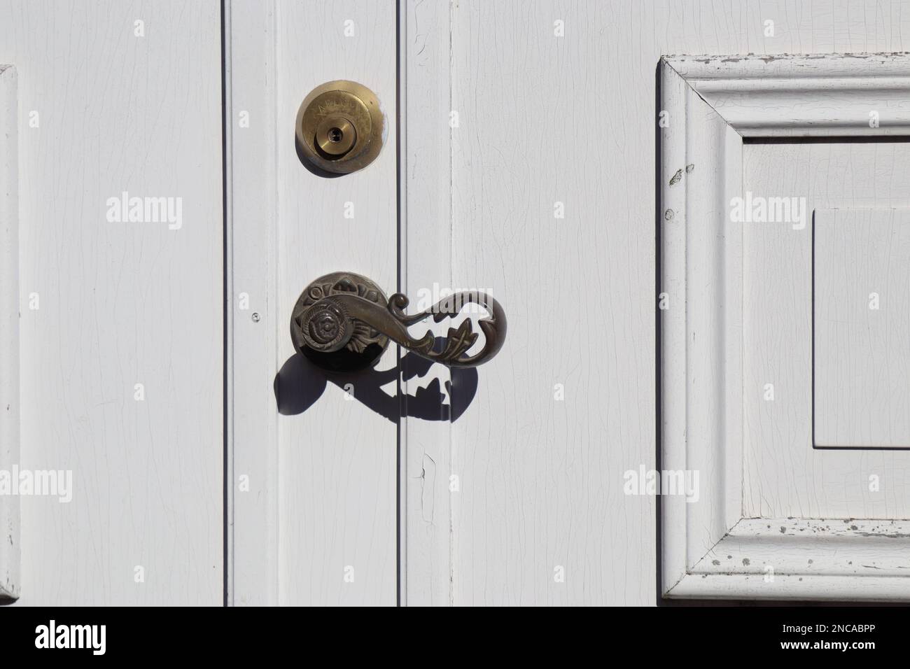 bronze floral metal door handle on white wooden door, old wooden door with metal handle. Old white garden doors. locked door, closed doors Stock Photo