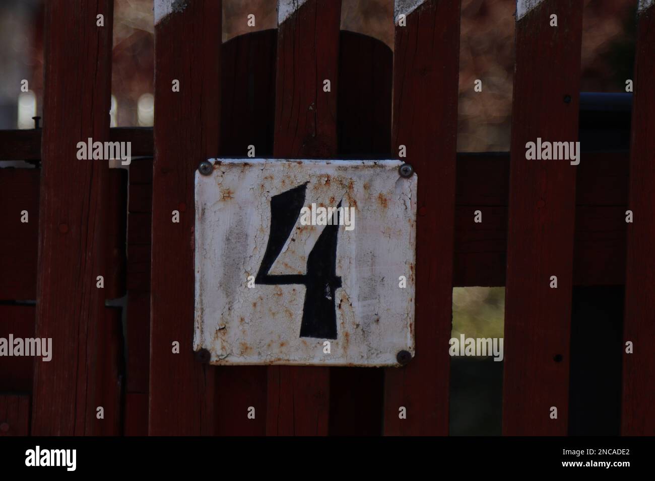 house number 4 wooden fence with a metal address sign, old rustic white