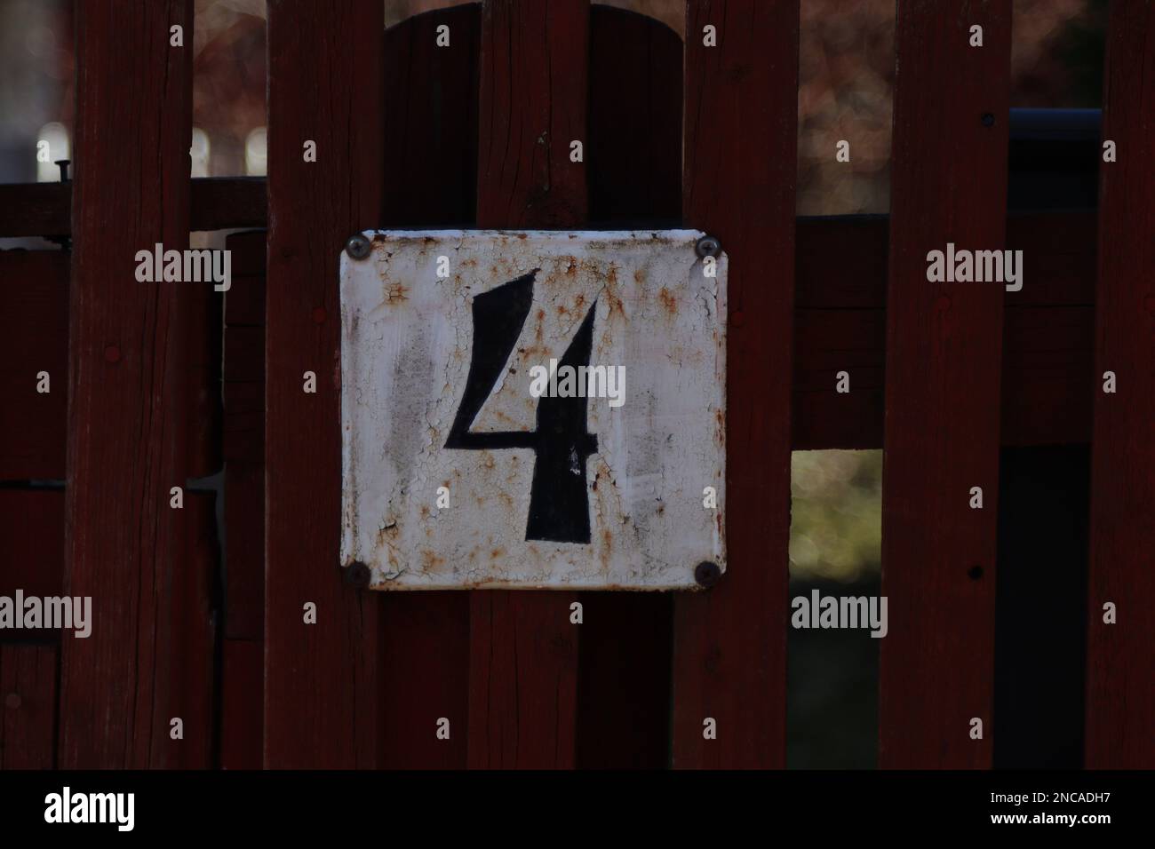 house number 4 wooden fence with a metal address sign, old rustic white background, black number four digit Stock Photo