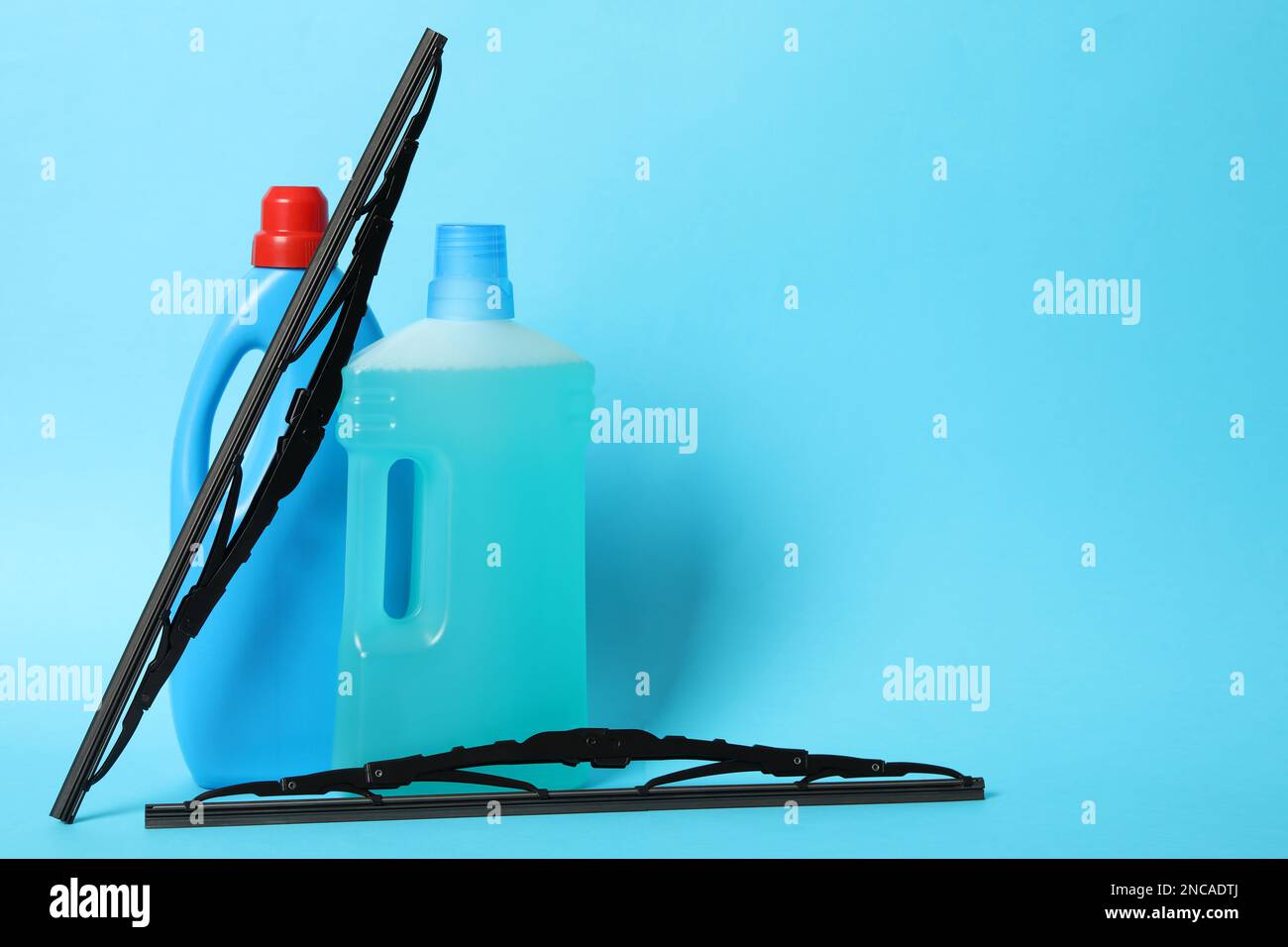 Bottles of windshield washer fluids and wipers on light blue background