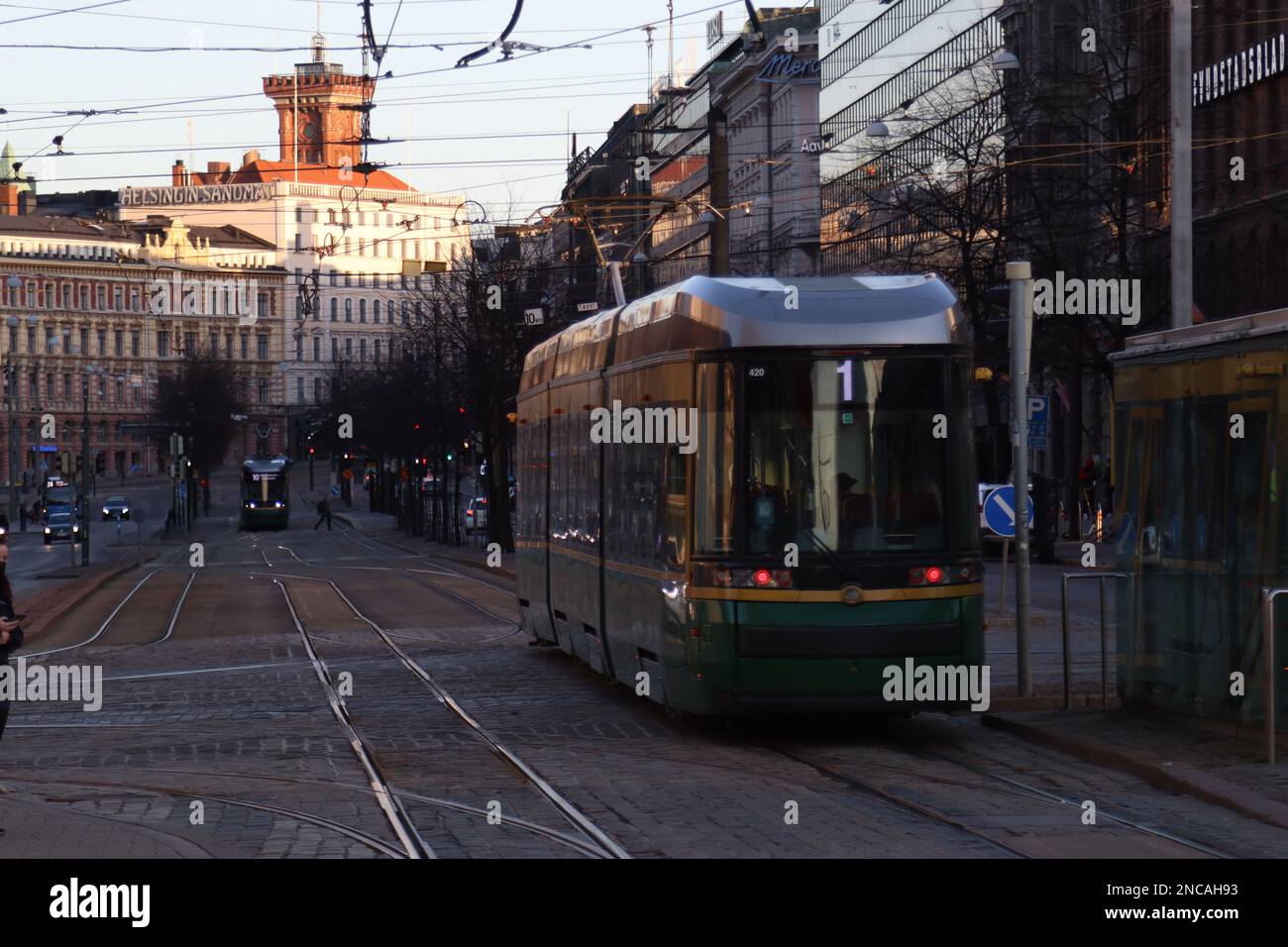 Public Tram With The Number Of The 1 Route Departs From A Stop On Mannerheim Avenue In Helsinki. Street In Kluuvi District In Evening Or Night Illumi Stock Photo